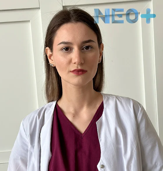 женщина врач в белом халате смотрит на зрителя